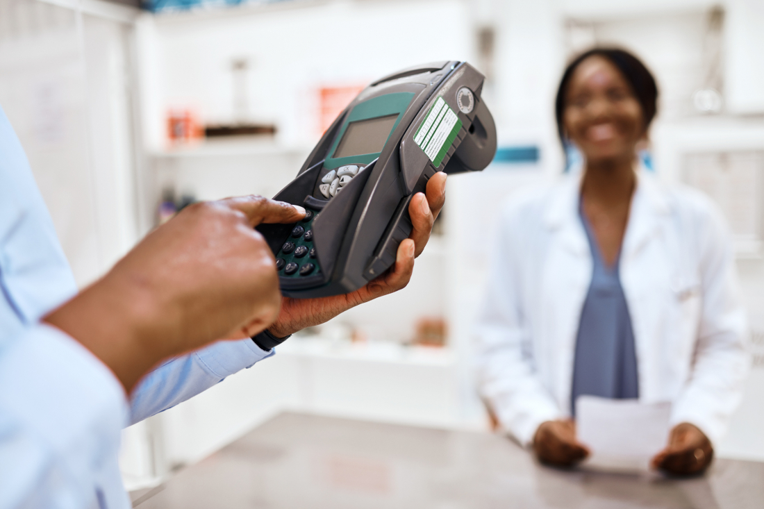 Customer entering his credit card pin number to pay for a purchase in a pharmacy.